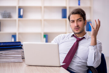 Obraz premium Young male employee and too much work in the office