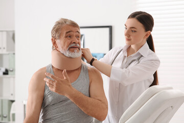 Orthopedist applying cervical collar onto patient's neck in clinic - Powered by Adobe