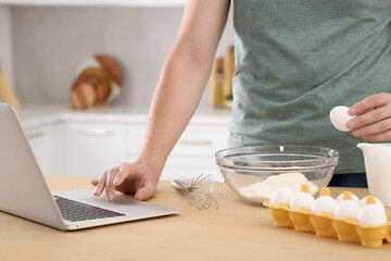 Man learning to cook with online video at wooden table in kitchen, closeup. Time for hobby