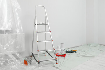 Metallic folding ladder and painting tools indoors