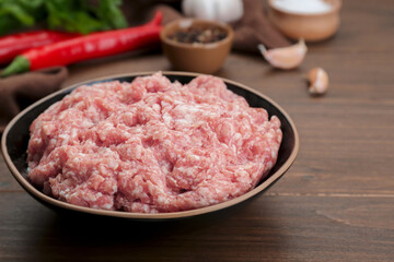 Bowl with raw fresh minced meat on wooden table, closeup