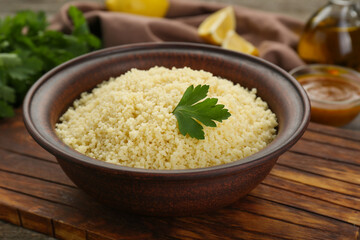 Tasty couscous with parsley on wooden board, closeup