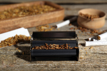 Roller with tobacco on old wooden table. Making hand rolled cigarettes