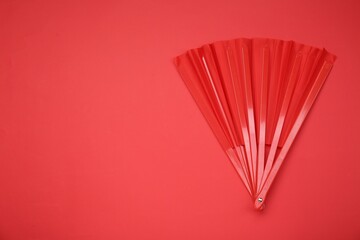 Bright color hand fan on red background, top view. Space for text