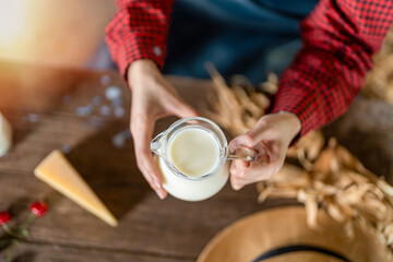 Obraz na płótnie Canvas Young female dairy farmer hand holding jug of fresh milk top view, dairy farm product concept