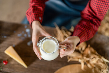 Fototapeta na wymiar Young female dairy farmer hand holding jug of fresh milk top view, dairy farm product concept