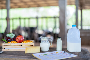 Fresh milk in glass on dark wooden table and blurred landscape with cows on pasture, healthy eating, rustic style, space for design