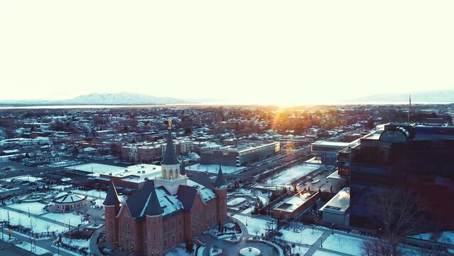 provo city center temple aerial during sunset sunrise with a bright orange sun flare over the city of provo utah