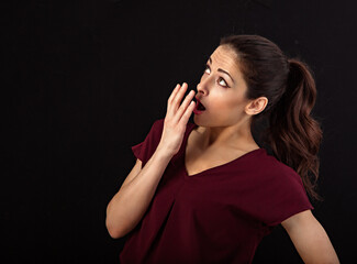Obraz premium Beautiful excited woman with long brown healthy hair style looking up and covering the mouth the hand. Healthy lifestyle and success business. Closeup portrait