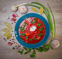 Traditional ukrainian borsch on wooden background. Red beet soup with sour cream and parsley....