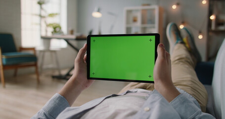 Close up shot of man using a laptop computer. Green screen mock up chroma key template. Hands holding a tablet computer with green mock up screen. A template for video conference or online store 