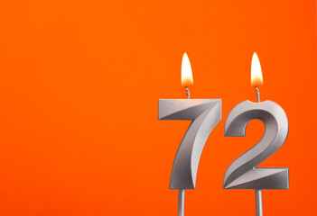 Number 72 - Silver Anniversary candle on orange background