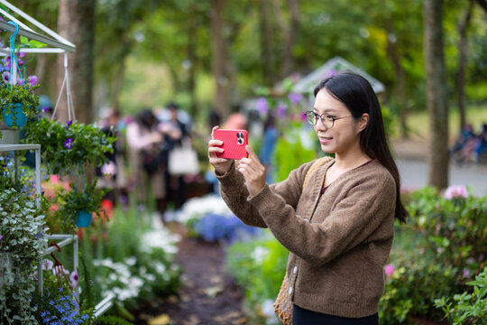 Woman take photo on cellphone in flower garden
