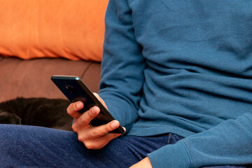 joven sentado en un sillon sosteniendo el telefono celular 