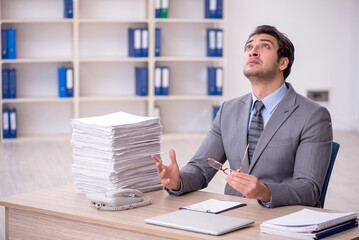 Young male employee and too much work at workplace