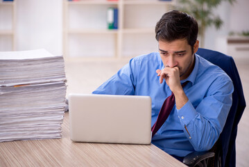 Young male employee and too much work in the office