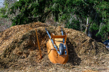 Getting ready for spring, yellow upside down wheelbarrow and shovel in a large pile of fresh wood...