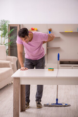 Young male contractor cleaning the house