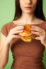 Woman holding burger with lettuce and tomato 