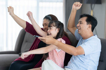 Happy asian family relaxing and watching tv at home