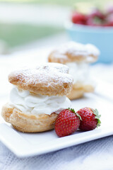 pastry on a white plate with whipped cream and strawberries