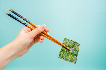 Young woman holding nori seaweed with wooden chopsticks. japanese traditional cuisine © Ekaterina