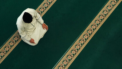 Top view of muslim man praying on the carpet at the mosque