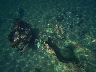 A rough rock below the water in Coron, Palawan in the Philippines with water reflecting the light.