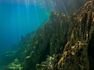 A rough rock below the water in Coron, Palawan in the Philippines with water reflecting the light.
