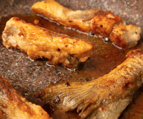The fish is fried in a frying pan in oil. Close-up.