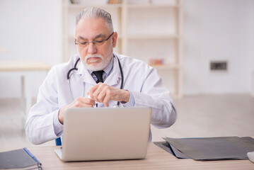 Old male doctor suggesting pills in the clinic