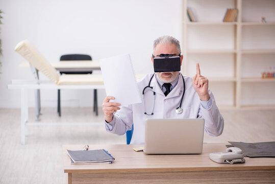 Old male doctor wearing virtual glasses in the clinic