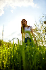 joyful woman posing in tall grass on a sunny day