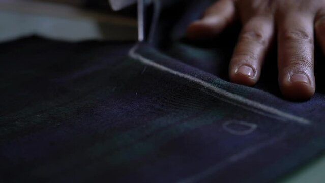 hand of a person cutting fabric with dressmaker scissors