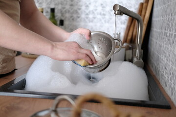 Close-up of a man washing dishes in the kitchen sink