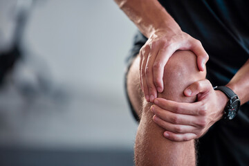 Hands, knee and pain with a sports man holding a joint injury while training in a gym for health....