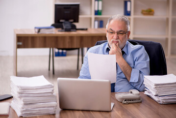 Obraz premium Old male employee and too much work in the office