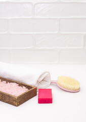 Towel, body brush, soap, sea salt on white bathroom background. Concept of self care, bath, spa. Copy space