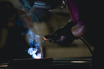 Industry worker welding iron pieces at work