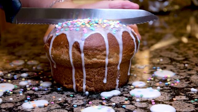 A woman cuts a cooked cruffin with raisins and candied fruits with a knife. Close-up. High quality 4k footage