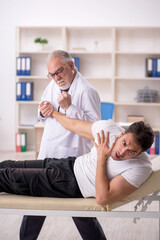 Fototapeta premium Young male doctor visiting old doctor chiropractor