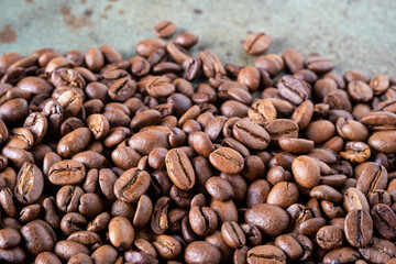 Close-up of roasted coffee beans on a green surface as a background. Selective focus.