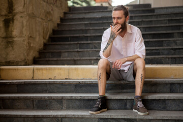 Tattoed and bearded guy posing outdoor in the city