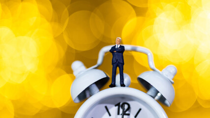Businessman figurine standing on alarm clock