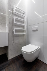 A luxurious interior in the bathroom with a bathroom, a shower on a shelf and a walk in the shower. White marble and dark brown floor. White cranes and plumbing