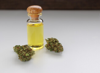 Glass bottle with herbal organic medicine CBD oil and medical cannabis bud on white background.