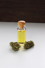 Glass bottle with herbal organic medicine CBD oil and medical cannabis bud on white background.