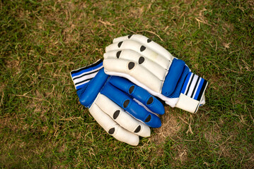 cricket gloves laying on grass playing field