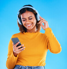 Happy woman, music headphones and phone in studio, blue background and happiness. Female model,...