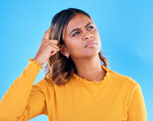 Thinking, confused and pensive woman in a studio with an idea, thoughtful or contemplating face expression. Deciding, doubtful and female model with wonder scratching head gesture by blue background.